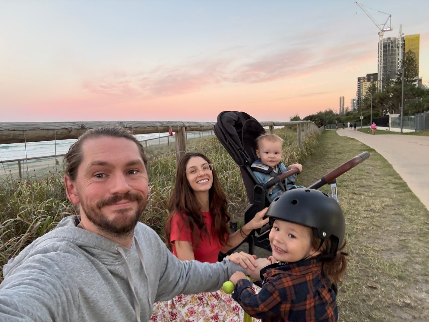 JC with his wife and two young sons on a beachside path at sunset